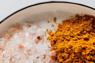 Salt and curry powder sit in a white dish with a dark rim