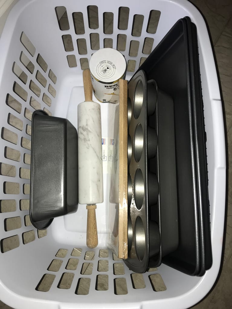A laundry basket holds kitchen pans, a rolling pin and salt.