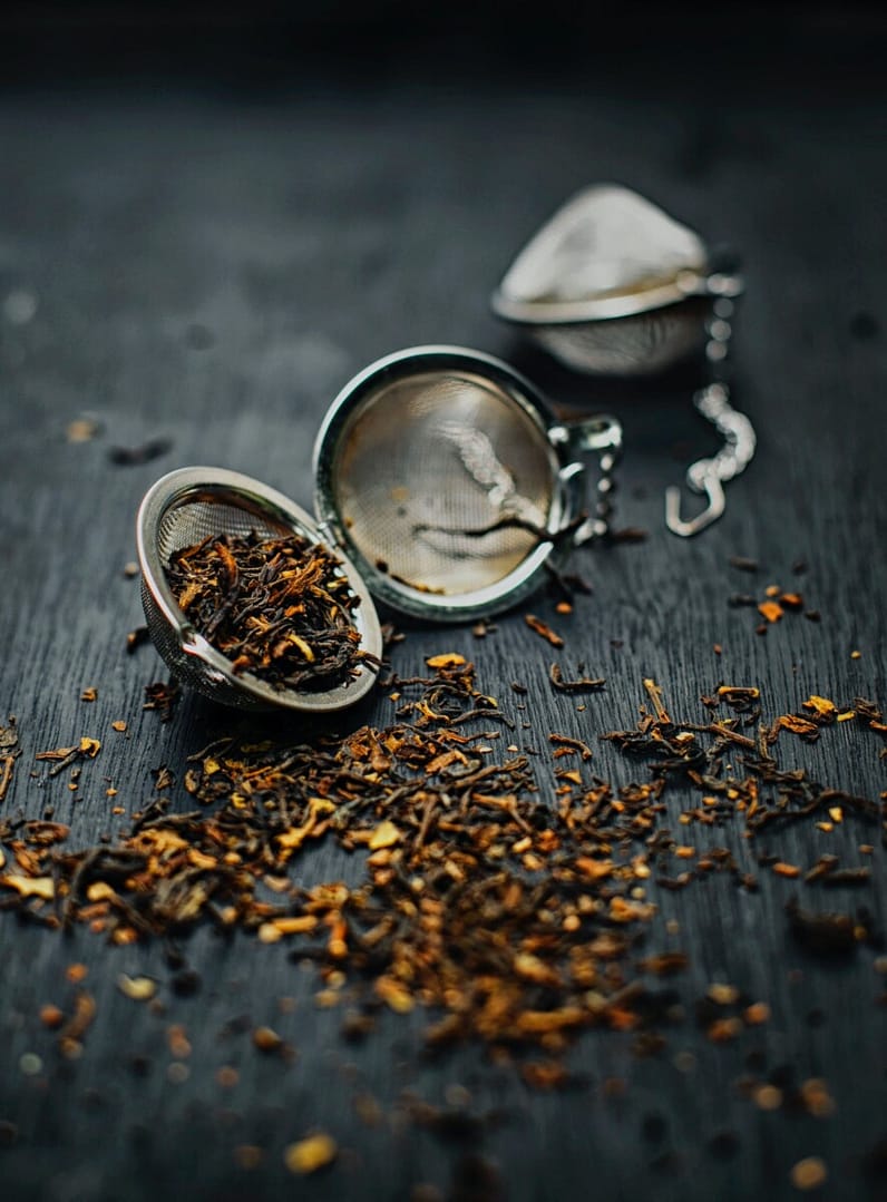 Grow your own tea and never be out of stock! An open tea ball with tea spills loose leaf tea on the table.