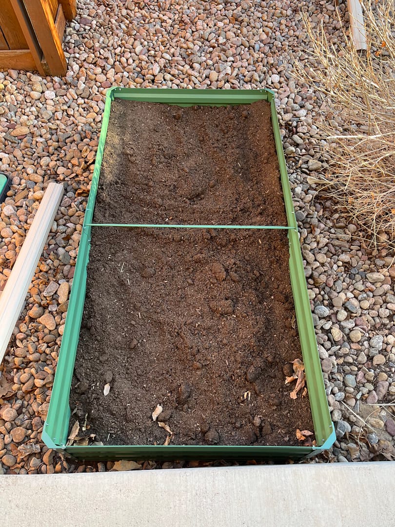Angie shares How To Fill A Raised Garden Bed - this bed is green metal and almost filled with dirt.