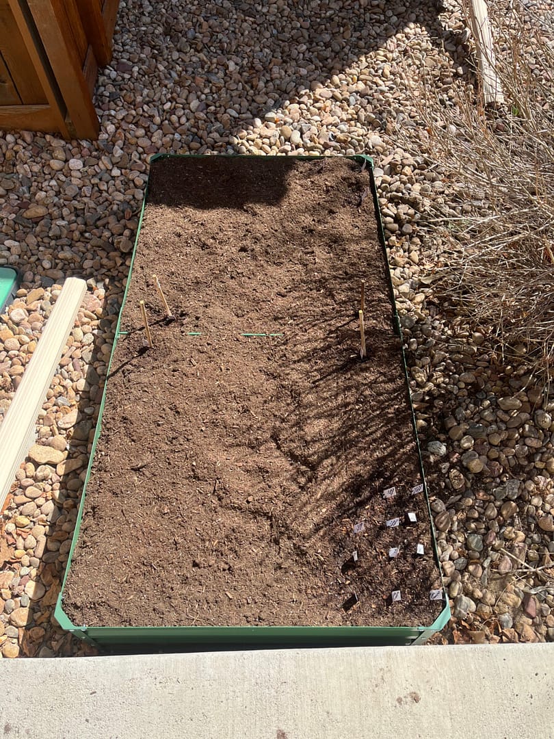 Angie shares How To Fill A Raised Garden Bed - this bed is green metal and filled with dirt..