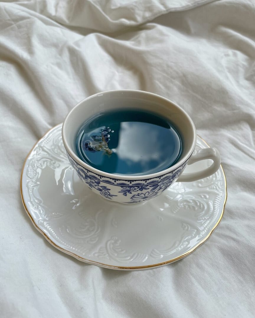 Beautiful butterfly pea flower tea sits in a white mug and the blue color really pops!